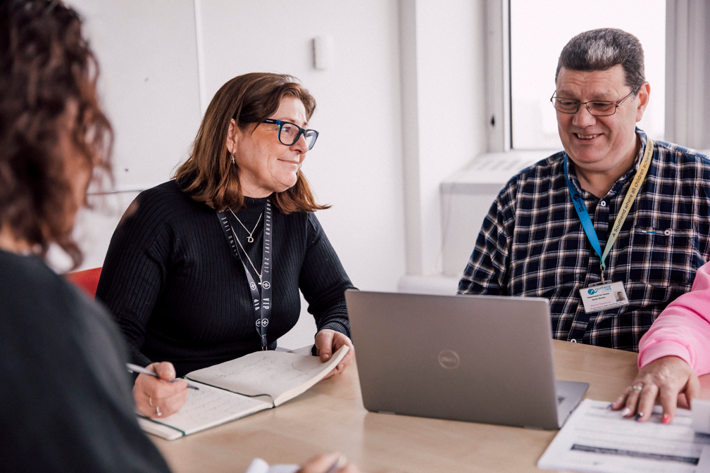 People in a meeting room discussing and working on laptops