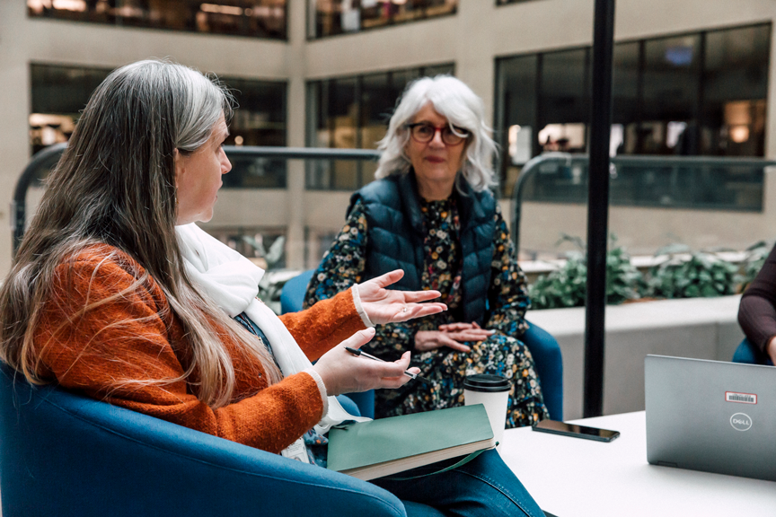 A group of female social workers sit in an atrium deep in conversation